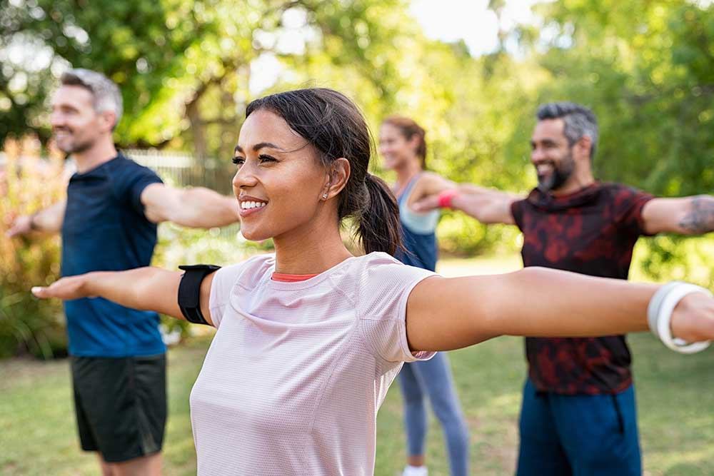 Outdoor scene of a group exercise class taking place in the park.