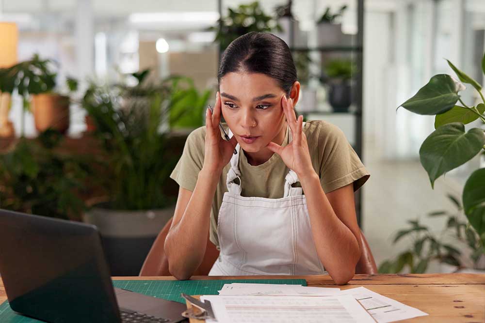 Employee sat at desk holding head in their hands